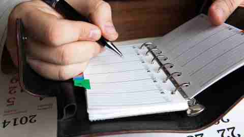 A man practices staying on task while writing things in his address book.