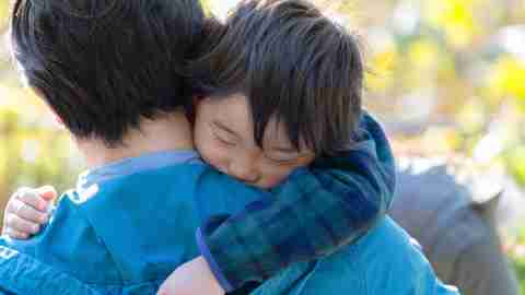 A boy with ADHD hugs his father after a hard day