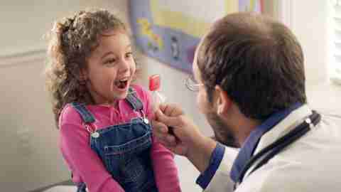 A doctor gives a girl a lollipop after teaching her about executive function.