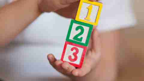 A child with ADHD holds 1,2,3 stacked blocks - close up