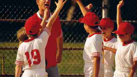 A baseball coach and his players with ADHD cheer after winning a game