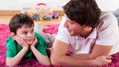 Young boy lying on the floor talking about the side effects of his ADHD medication with his dad