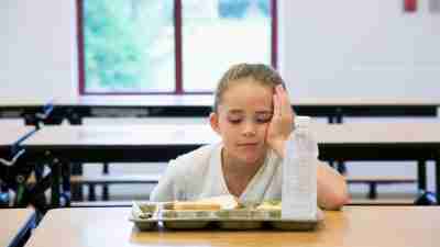 Socially rejected by her peers, a sad girl eats lunch alone.