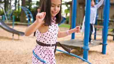 A girl is hula-hooping on the playground, but ostracized for being hyperactive.