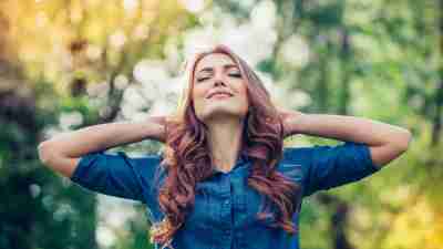 Woman with ADHD standing outside with hands behind head and eyes closed relived to be stress-free