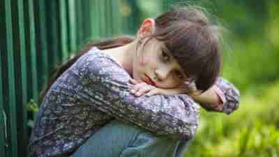 A young girl dealing with ADHD inattention, sitting with her head on her knees