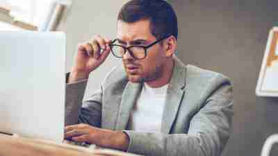 Man with ADHD looking confused at a laptop because for an accurate diagnosis you'll need a qualified clinician and a solid evaluation.