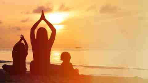 Family doing yoga on the beach