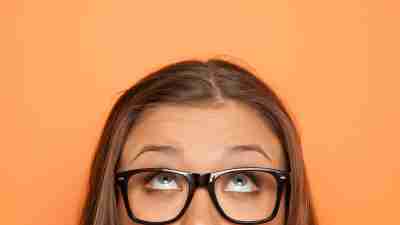 half portrait of a young girl with glasses looking up