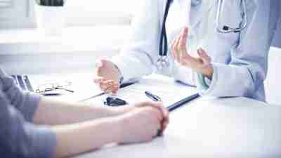 Close up of doctor and  patient  sitting at the desk near the window in hospital