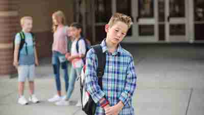 Sad boy feeling left out, teased and bullied by his classmates. Unhappy boy having problems fitting in with others at school