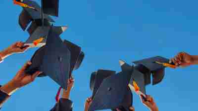 The students holding a shot of graduation cap by their hand in a bright sky during ceremony success graduates at the University, Concept of Successful Education in Hight School,Congratulated Degree