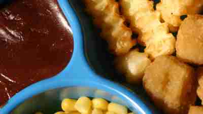 A close-up shot of food on a TV dinner plate.