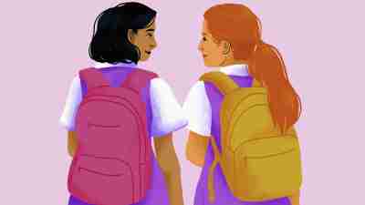 Smiling schoolgirl friends in school uniforms with backpacks. Autism in girls looks different. Take this symptoms of autism in girls self-test to see if your child is showing signs of neurodivergence.