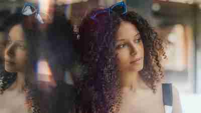 Woman staring off into distane leaning against a reflective surface