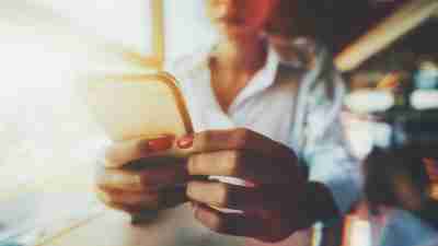 A woman hyperfocuses on her phone in a busy cafe