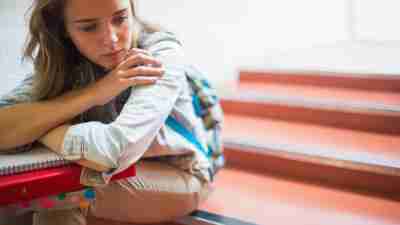 Sad lonely ADHD female student sitting on stairs