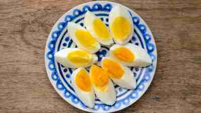 Plate with sliced pieces of boiled egg on wooden table makes for a good breakfast for ADHD children