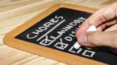 Person with ADHD checking off list of chores from mini blackboard