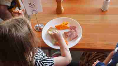 Little girl with ADHD eating plate of food at diner