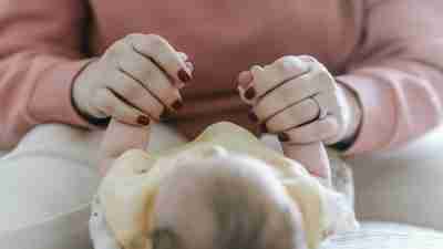 A closeup of a mother hands holding her infant's hands. Active parenting is a key part of postpartum depression recovery.