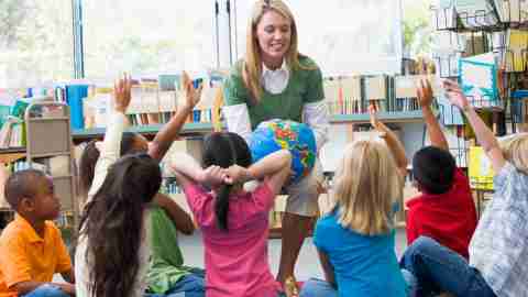 Children with ADHD at school sitting around teacher.