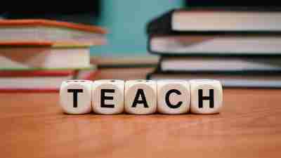 Blocks that spell out teach on a wooden desk