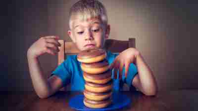 A boy with ADHD, staring at a tall pile of donuts with sugar
